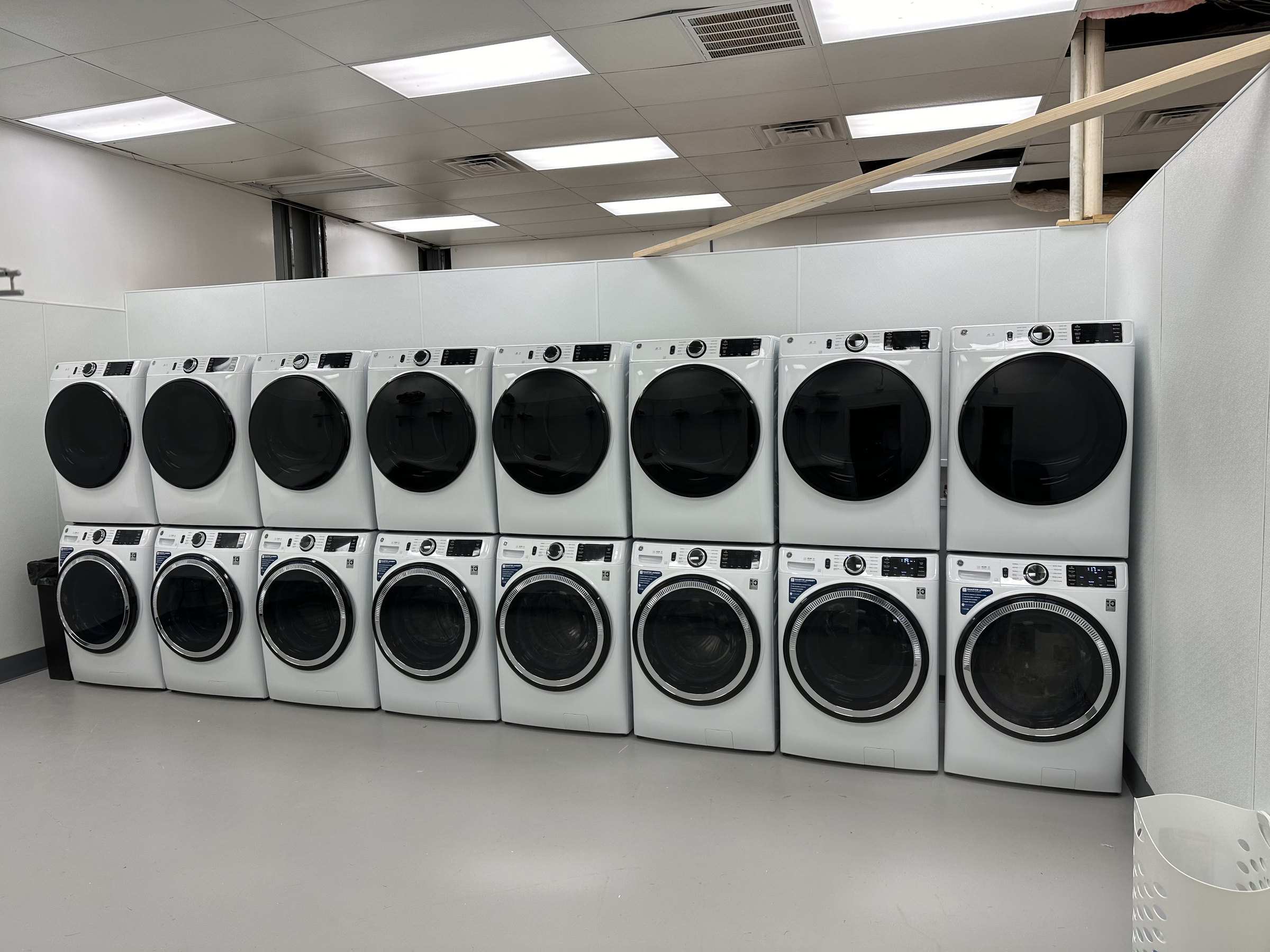 The on-site laundromat: a long wall of stacked white front-load washers and dryers.